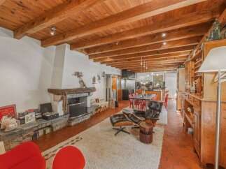 Experience rustic charm in this spacious living area featuring a grand stone fireplace and exposed wooden beams.