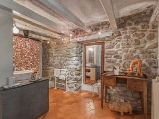Experience rustic charm in this unique bathroom featuring exposed stone walls and wooden beams.