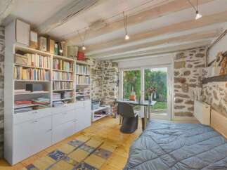 Discover this charming room featuring exposed wooden beams and rustic stone walls, creating a unique and cozy atmosphere.