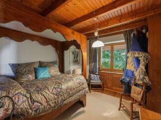 Experience rustic charm in this cozy bedroom featuring a beautiful wooden canopy bed adorned with a vibrant, patterned quilt.