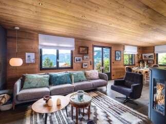 Experience luxurious mountain living in this stunning chalet, featuring a cozy living area with a modern fireplace and breathtaking panoramic views.