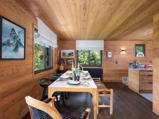 Experience rustic charm in this beautifully appointed dining room, featuring warm wood paneling throughout and a large window offering scenic views.