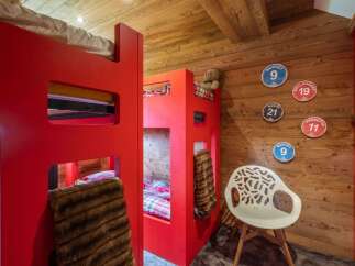 Experience cozy mountain living in this charming alpine bedroom, featuring vibrant red bunk beds perfect for family adventures.