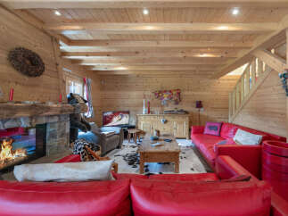 Experience rustic charm in this cozy log cabin living room, featuring a roaring fireplace and comfortable red leather seating.