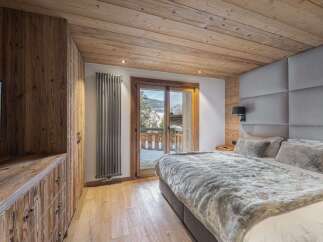 Experience luxurious alpine living in this beautifully appointed bedroom, featuring a cozy king-size bed with plush faux fur throws and a stunning upholstered headboard.