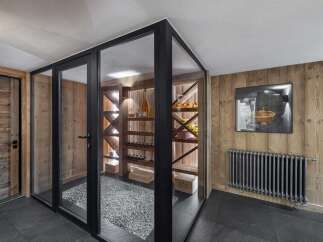 Experience sophisticated wine storage in this modern wine cellar, featuring glass walls and rustic wooden shelving.