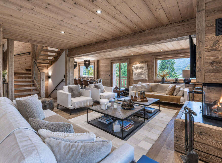 Experience luxurious mountain living in this stunning chalet living room, featuring a cozy fireplace and ample natural light.