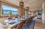 Experience luxurious mountain living in this stunning dining room, featuring a grand wooden table set for a feast and surrounded by elegant leather chairs.