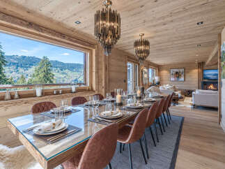 Experience luxurious mountain living in this stunning dining room, featuring a grand wooden table set for a feast and surrounded by elegant leather chairs.