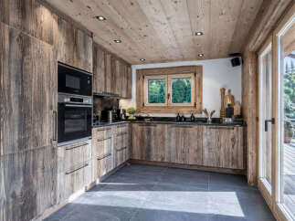 Experience rustic charm in this mountain kitchen, featuring custom wood cabinetry and a sleek built-in oven and microwave.