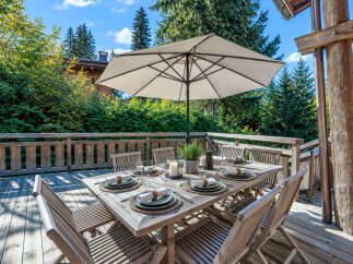 Enjoy al fresco dining on this charming wooden deck, complete with a large table set for six and a spacious umbrella for shade.