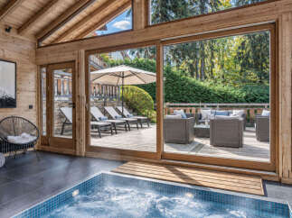 Indulge in ultimate relaxation in this luxurious indoor spa area, featuring a bubbling hot tub with stunning views of the outdoor patio.