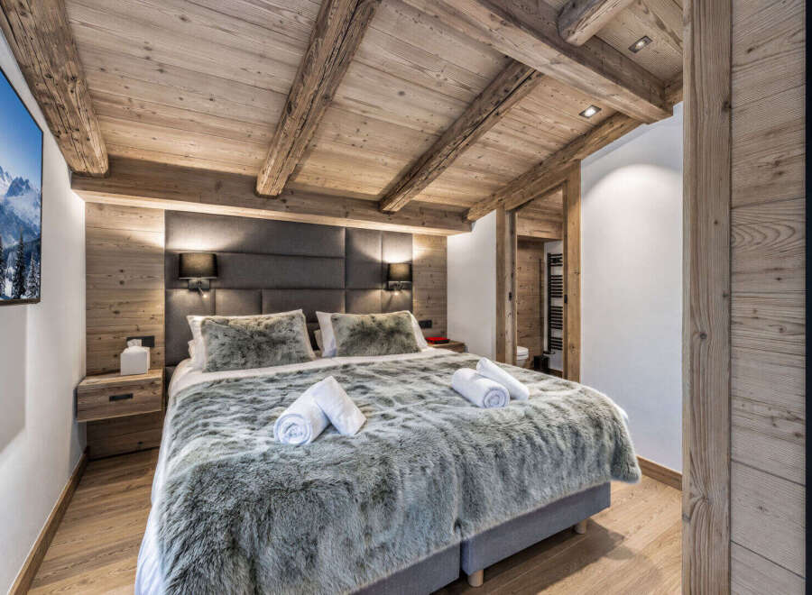 Experience ultimate comfort in this luxurious bedroom, featuring a plush king-size bed adorned with soft, faux fur throws and crisp white towels.