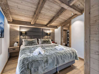 Experience ultimate comfort in this luxurious bedroom, featuring a plush king-size bed adorned with soft, faux fur throws and crisp white towels.