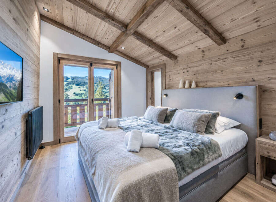 Experience ultimate comfort in this master bedroom, featuring a luxurious king-size bed with plush bedding and a stunning mountain view.