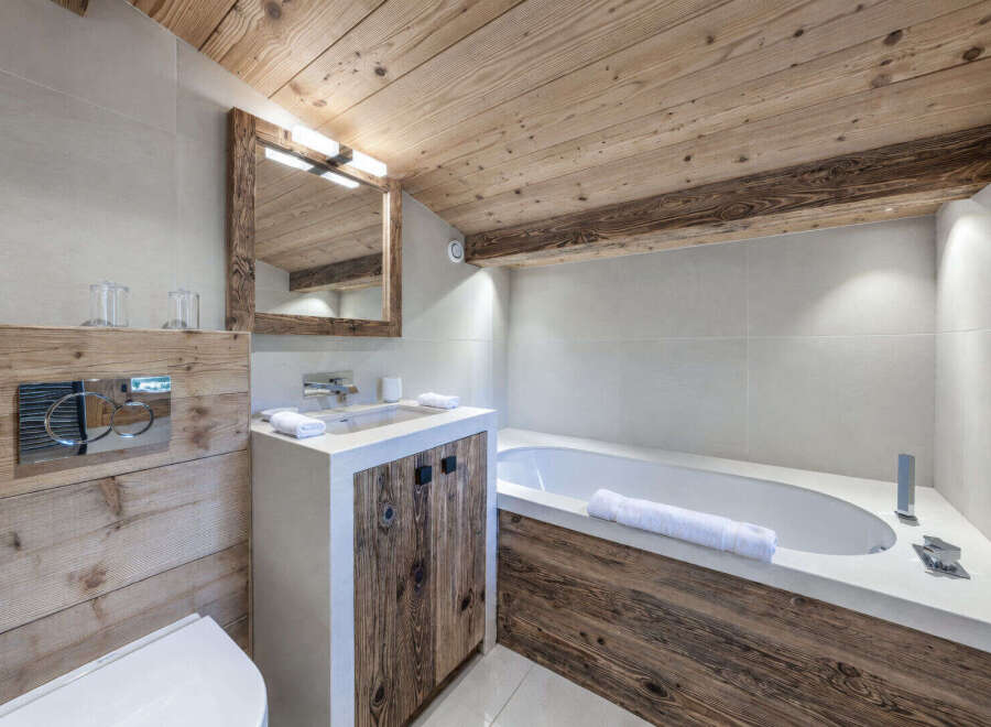 Experience rustic luxury in this mountain-inspired bathroom, featuring a modern concrete vanity with reclaimed wood accents and a deep soaking tub.