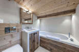 Experience rustic luxury in this mountain-inspired bathroom, featuring a modern concrete vanity with reclaimed wood accents and a deep soaking tub.