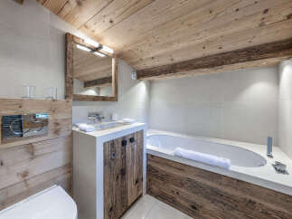 Experience rustic luxury in this mountain-inspired bathroom, featuring a modern concrete vanity with reclaimed wood accents and a deep soaking tub.