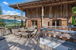 Enjoy breathtaking mountain views from this stunning wooden chalet's expansive deck.