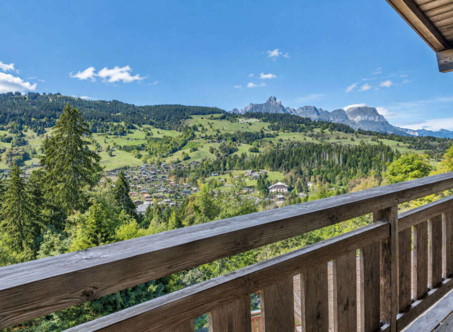 Experience breathtaking mountain views from this charming property, featuring a rustic wooden balcony perfect for enjoying the serene alpine landscape.