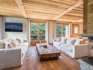 Experience luxurious mountain living in this stunning chalet, featuring a spacious living area with a rustic wooden coffee table and plush white sofas.