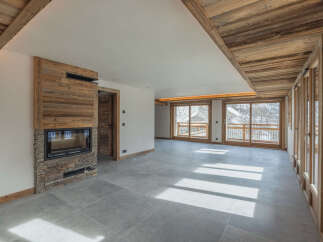 Experience luxurious mountain living in this stunning property featuring a modern fireplace with natural wood accents and stone detailing.