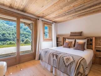 Experience serene mountain living in this charming bedroom, featuring a cozy bed adorned with a rustic blanket and plaid pillows.