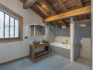 Experience rustic charm and modern luxury in this stunning bathroom, featuring exposed wooden beams and a sleek glass-enclosed shower.