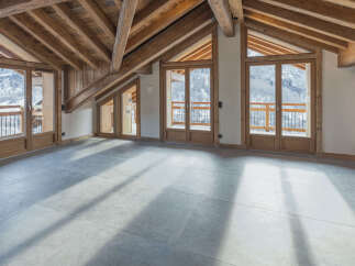 Experience breathtaking mountain views from this spacious attic room, featuring a stunning exposed wooden beam ceiling and large glass doors that open to a private balcony.