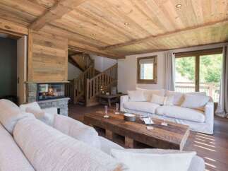 Experience rustic luxury in this stunning living room, featuring a cozy stone fireplace and exposed wooden beams that create a warm, inviting atmosphere.