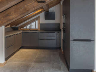 Experience modern living in this stylish attic kitchen, featuring sleek grey cabinetry and a unique triangular window that floods the space with natural light.