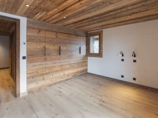 Experience rustic charm in this beautifully appointed room featuring a stunning wood-paneled ceiling and walls, complemented by a light wood floor.
