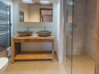 Experience rustic charm in this bathroom featuring a double vanity with stone vessel sinks atop a reclaimed wood counter.