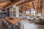 Experience luxury mountain living in this stunning chalet, featuring a grand open-plan living space with exposed wooden beams and a cozy fireplace.