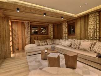 Experience rustic luxury in this stunning living room, featuring warm wood paneling throughout and a plush sectional sofa adorned with decorative pillows.