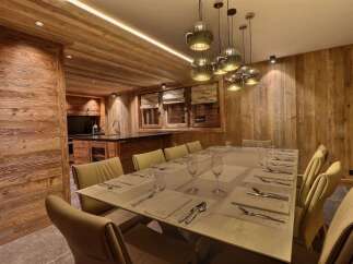 Experience luxurious mountain living in this stunning dining room, featuring rustic wood paneling and a sleek, modern table setting.