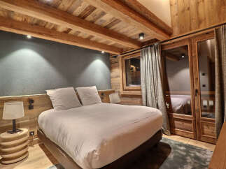 Experience rustic luxury in this charming bedroom, featuring exposed wooden beams and a cozy, inviting atmosphere.