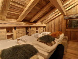 Experience rustic luxury in this charming attic bedroom, featuring exposed wooden beams and walls that exude warmth and character.