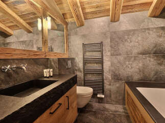 Experience rustic luxury in this stunning bathroom featuring a deep stone sink and a sleek, modern toilet.