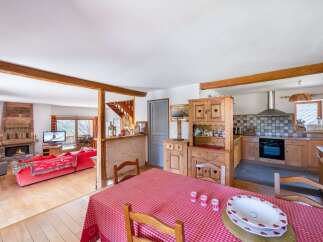 Experience cozy living in this charming mountain retreat, featuring a rustic living area with a stone fireplace and a spacious red sofa perfect for relaxing.