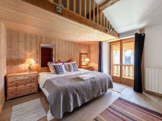 Experience cozy mountain living in this charming bedroom featuring warm wood paneling and a comfortable queen-sized bed.