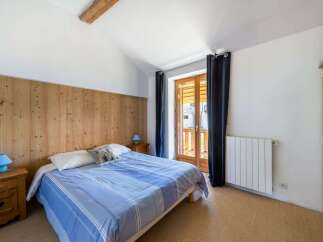 This charming bedroom features a cozy wooden headboard and a comfortable bed dressed in blue striped linens.