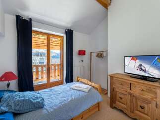 Experience cozy mountain living in this charming bedroom, featuring a comfortable single bed adorned with blue patterned bedding.