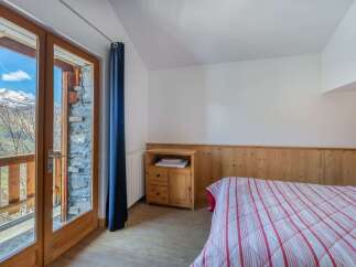 Experience breathtaking mountain views from this charming bedroom, featuring a cozy bed with a red and white striped comforter.