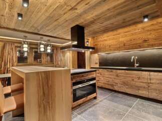 Experience rustic luxury in this stunning mountain kitchen, featuring warm, natural wood paneling throughout the walls and ceiling.