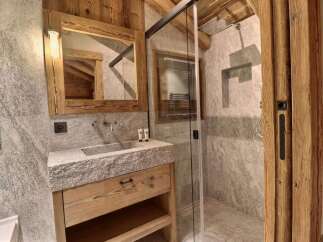Experience rustic luxury in this charming bathroom featuring a unique stone sink atop a wooden vanity.