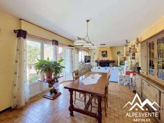 Experience rustic charm in this inviting dining and living area, featuring a large wooden dining table perfect for family gatherings.