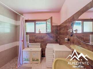 This charming bathroom features a tiled shower area with a pink curtain, complemented by a decorative cabinet and a white radiator.