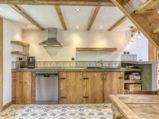 Experience rustic charm in this cozy kitchen featuring exposed wooden beams and a charming tiled backsplash.