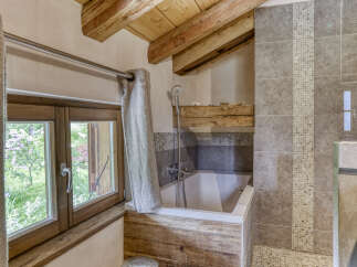 Experience rustic charm in this bathroom featuring a deep soaking tub surrounded by natural wood accents and elegant tilework.